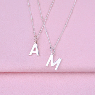 Close up detail of modern initial letter charm necklaces shown close up