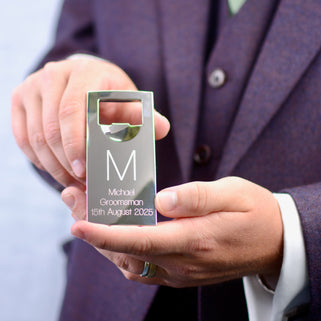 Silver Bottle Opener with personalised initial "M" engraved in the centre and "Michael Groomsman 15th August 2025" engraved below, shown in close up with groomsman model.