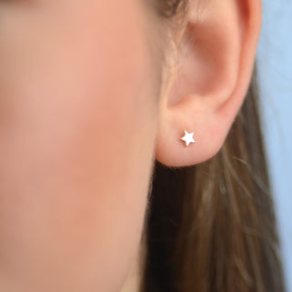 Gold Mini Star Stud Earrings shown close up on model