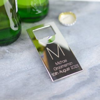 Silver Bottle Opener with personalised initial "M" engraved in the centre and "Michael Groomsman 15th August 2025" engraved below, shown in close up shot with beer bottle.