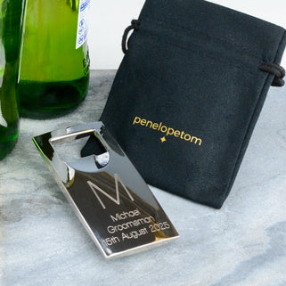 Silver Bottle Opener with personalised initial "M" engraved in the centre and "Michael Groomsman 15th August 2025" engraved below, shown in close up shot with Peneloeptom black linen pouch