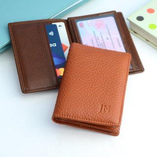 Close up of tan card holder with debossed initials and brown wallet open behind