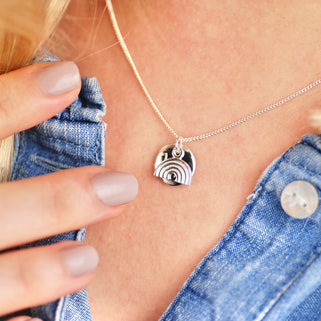 Sterling silver rainbow necklace with personalised circle disc engraved with "Hope" shown in close up shot on model.