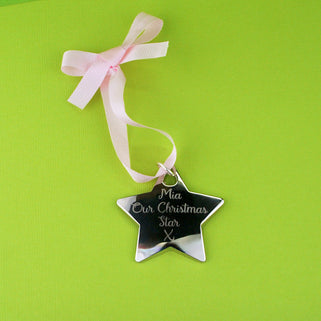 Christmas Star Tree Decoration with Personalised message "Mia Our Christmas Star X" engraved on the front with white ribbon shown in close up shot on green background