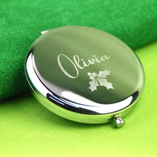 Personalised Christmas Holly Compact Mirror with "Olivia" engraved on the front shown in close up shot on green background