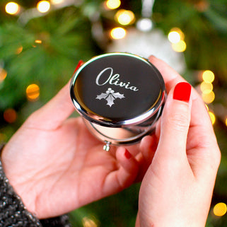 Personalised Christmas Holly Compact Mirror with "Olivia" engraved on the front shown in close up shot held by model