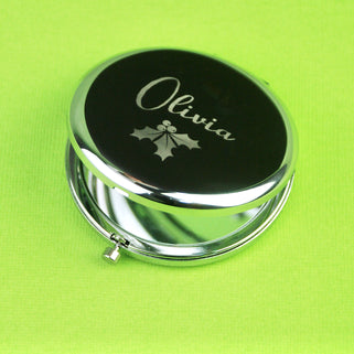 Personalised Christmas Holly Compact Mirror with "Olivia" engraved on the front shown in close up shot on green background