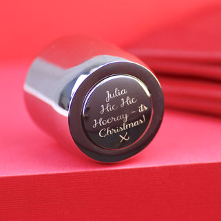 Prosecco Champagne Bottle Stopper with personalised message "Julia Hic Hic Hooray - its Christmas! x" engraved on the front, shown in close up shot of red background.