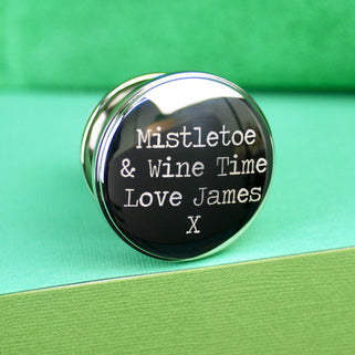 Christmas Wishes Wine Bottle Stopper with Personalised message "Mistletoe & Wine Time Love James X" engraved on top of stopper shown in close up shot on green background