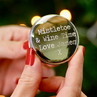 Christmas Wishes Wine Bottle Stopper with Personalised message "Mistletoe & Wine Time Love James X" engraved on top of stopper shown in close up shot held by model